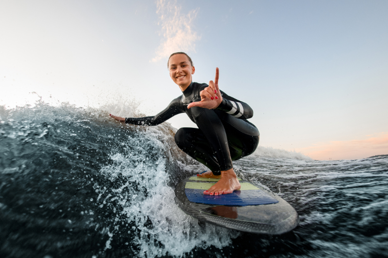Smiling woman sits on wakesurf board and rides the wave